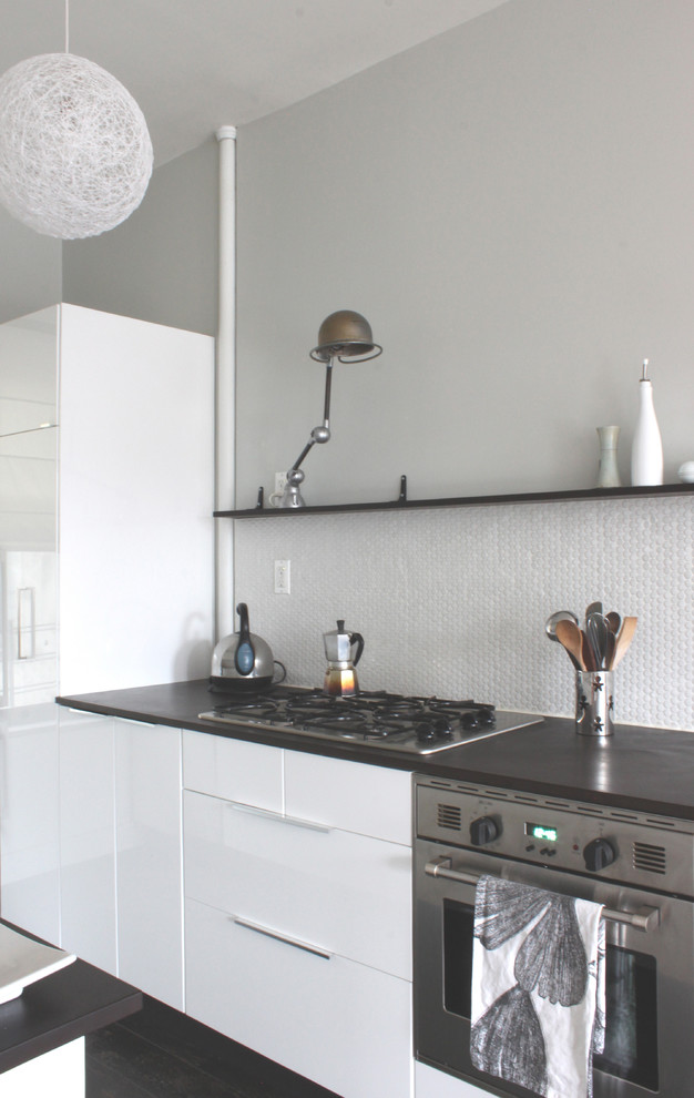 Imagen de cocina minimalista con armarios con paneles lisos, salpicadero blanco y con blanco y negro