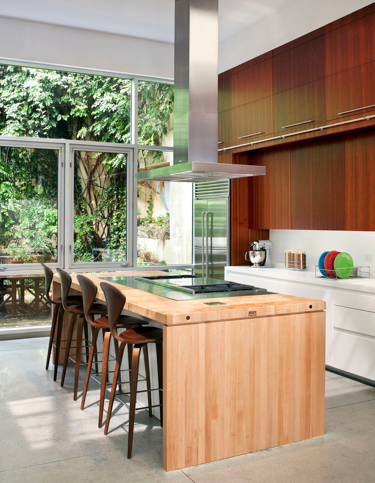 Diseño de cocina minimalista con armarios con paneles lisos, puertas de armario de madera en tonos medios y electrodomésticos de acero inoxidable
