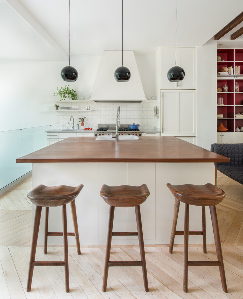 Contemporary galley open plan kitchen in Portland with a built-in sink, recessed-panel cabinets, white cabinets, wood worktops, white splashback, metro tiled splashback and integrated appliances.