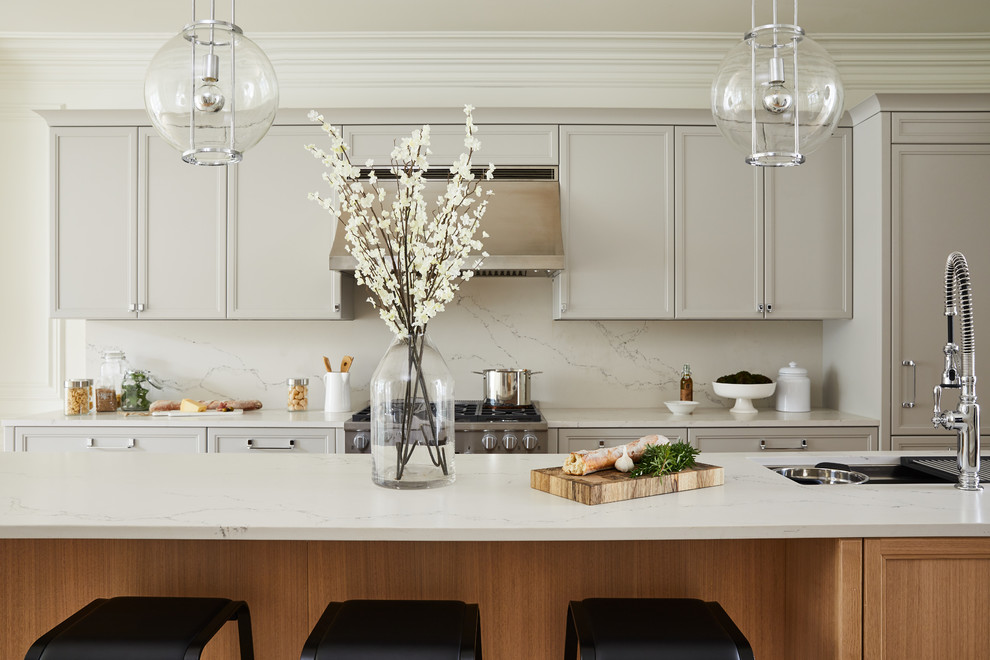 Exempel på ett mellanstort klassiskt vit vitt kök, med en undermonterad diskho, skåp i shakerstil, grå skåp, bänkskiva i kvarts, vitt stänkskydd, stänkskydd i marmor, integrerade vitvaror, mellanmörkt trägolv, en köksö och beiget golv