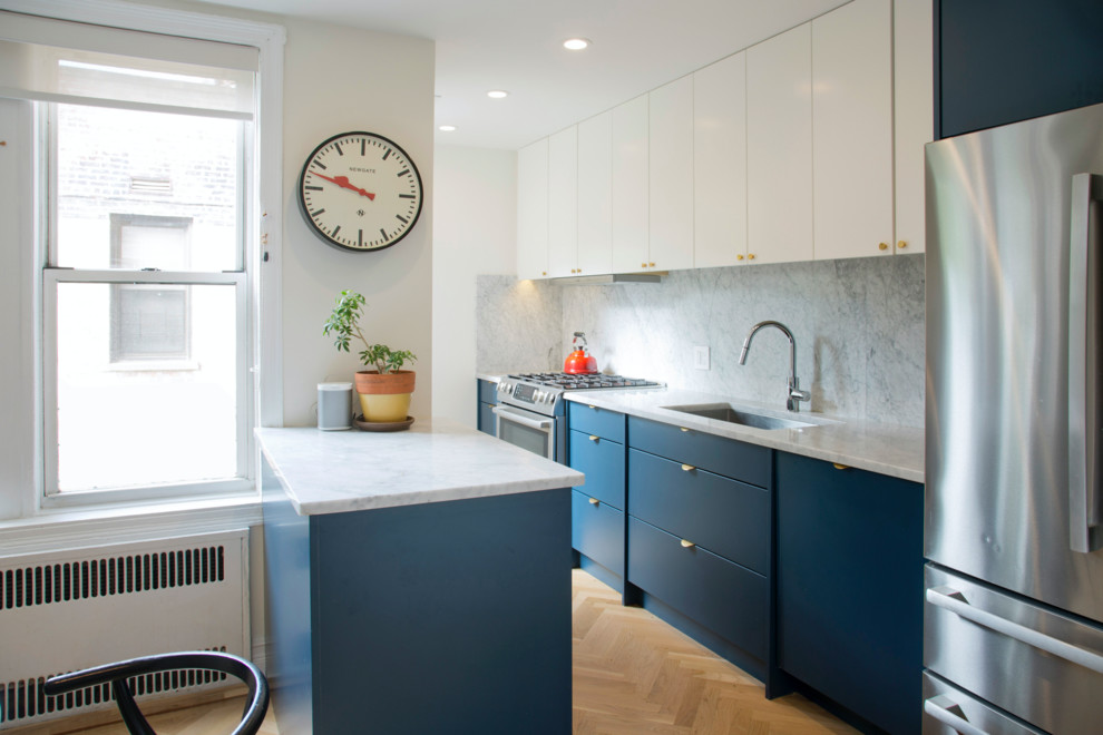 Example of a small trendy galley light wood floor and brown floor eat-in kitchen design in New York with an undermount sink, flat-panel cabinets, blue cabinets, marble countertops, white backsplash, marble backsplash, stainless steel appliances, a peninsula and white countertops