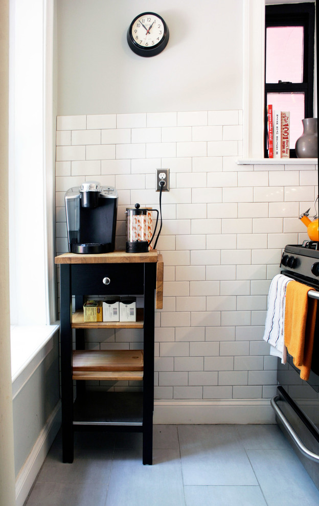 ニューヨークにある低価格の小さなインダストリアルスタイルのおしゃれなI型キッチン (シングルシンク、フラットパネル扉のキャビネット、白いキャビネット、御影石カウンター、白いキッチンパネル、サブウェイタイルのキッチンパネル、シルバーの調理設備、磁器タイルの床、グレーの床、黒いキッチンカウンター) の写真