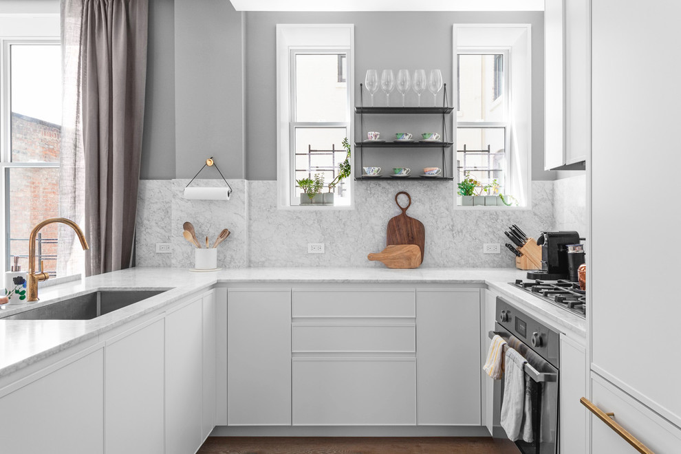 Exempel på ett modernt vit vitt u-kök, med marmorbänkskiva, stänkskydd i marmor, en undermonterad diskho, släta luckor, vita skåp, vitt stänkskydd, mellanmörkt trägolv, en halv köksö och brunt golv