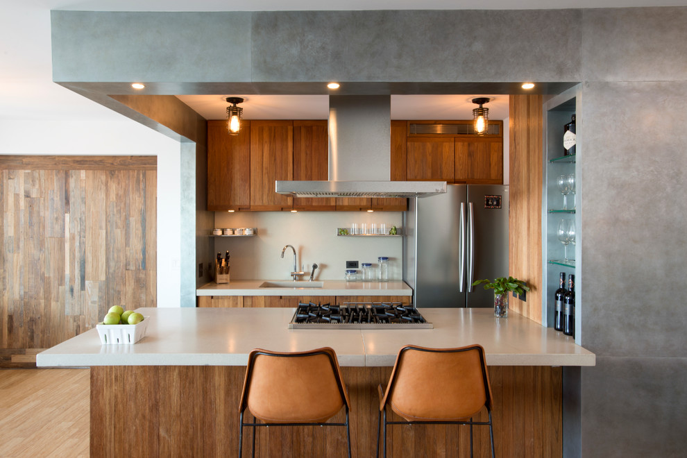 Photo of a small contemporary kitchen in New York with an island, flat-panel cabinets, medium wood cabinets, stainless steel appliances, bamboo flooring, concrete worktops, white splashback and a submerged sink.