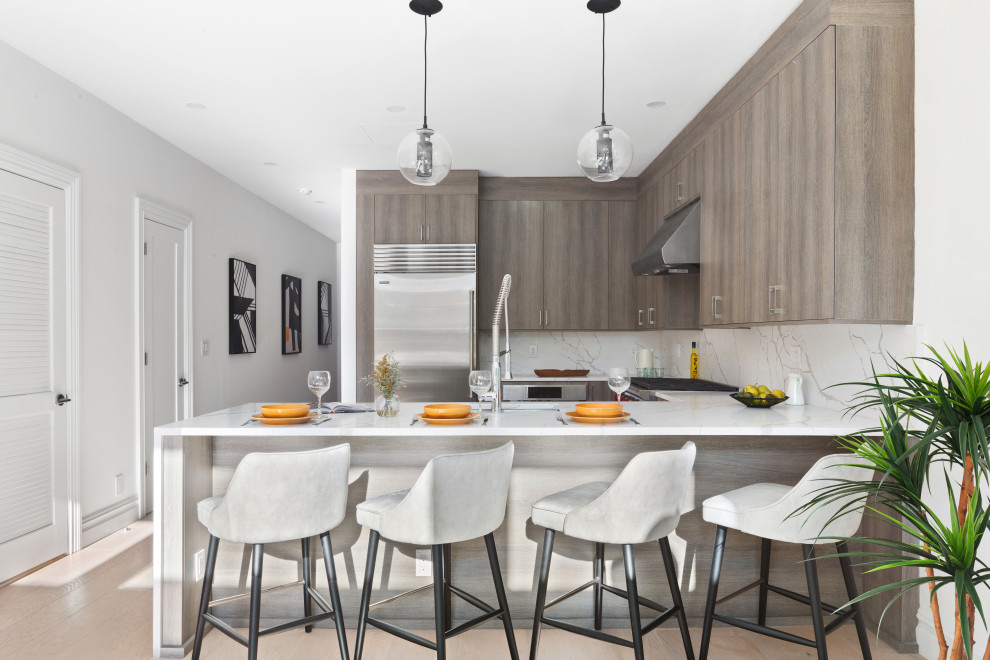 Mid-sized trendy u-shaped beige floor kitchen photo in Miami with an undermount sink, flat-panel cabinets, medium tone wood cabinets, white backsplash, stainless steel appliances, a peninsula and white countertops