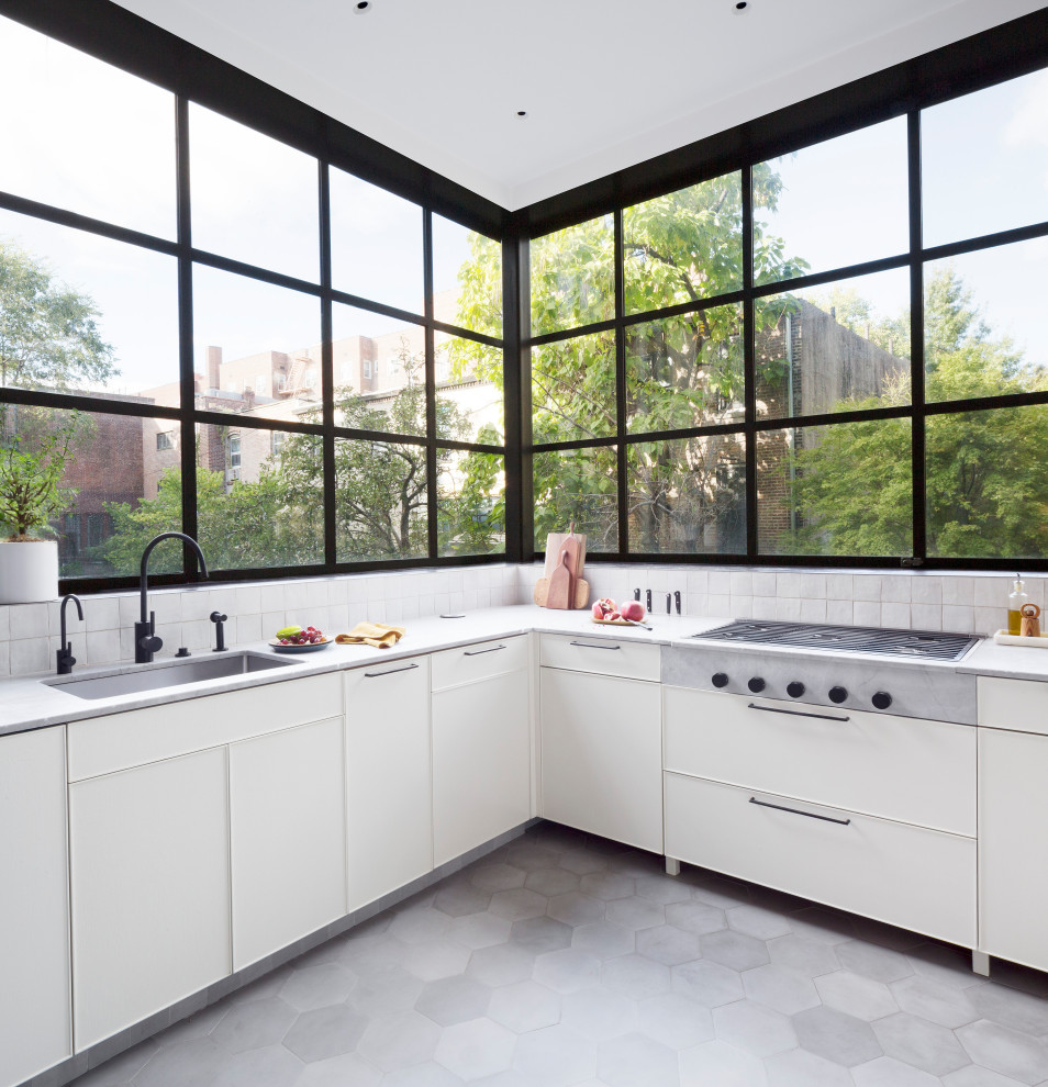 Foto på ett stort funkis grå kök, med en undermonterad diskho, släta luckor, gröna skåp, marmorbänkskiva, grått stänkskydd, stänkskydd i cementkakel, rostfria vitvaror, cementgolv, en halv köksö och grått golv