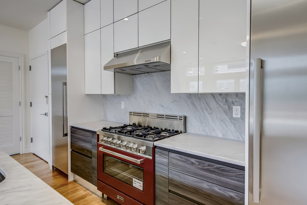 Inspiration for a medium sized modern single-wall open plan kitchen in New York with a built-in sink, flat-panel cabinets, white cabinets, engineered stone countertops, stone slab splashback, stainless steel appliances, light hardwood flooring, brown floors, multi-coloured splashback and an island.