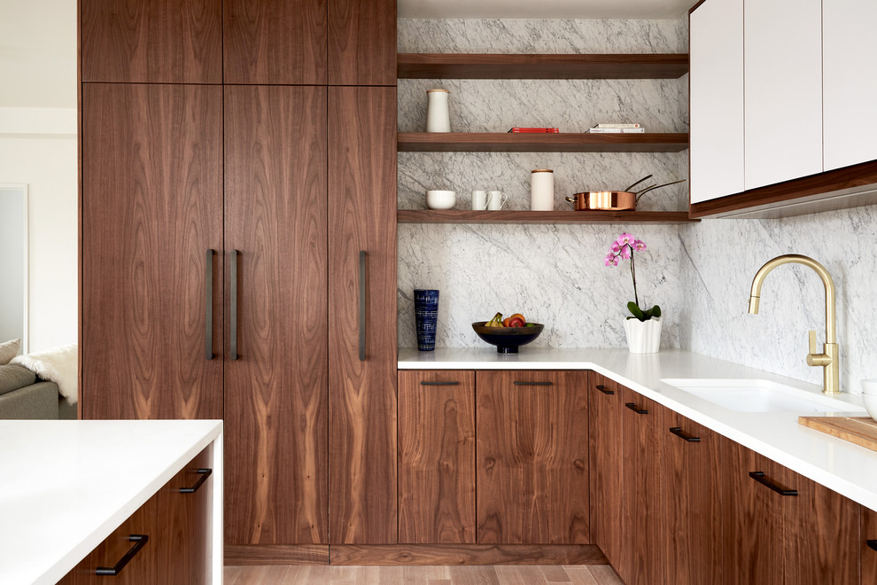 Moderne Küche in L-Form mit Unterbauwaschbecken, flächenbündigen Schrankfronten, dunklen Holzschränken, Küchenrückwand in Weiß, Rückwand aus Marmor, dunklem Holzboden, Kücheninsel und braunem Boden in New York