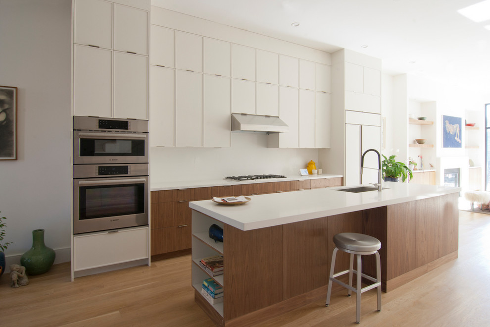 Inredning av ett modernt mellanstort vit linjärt vitt kök och matrum, med en undermonterad diskho, släta luckor, vita skåp, bänkskiva i koppar, integrerade vitvaror, ljust trägolv, en köksö och brunt golv