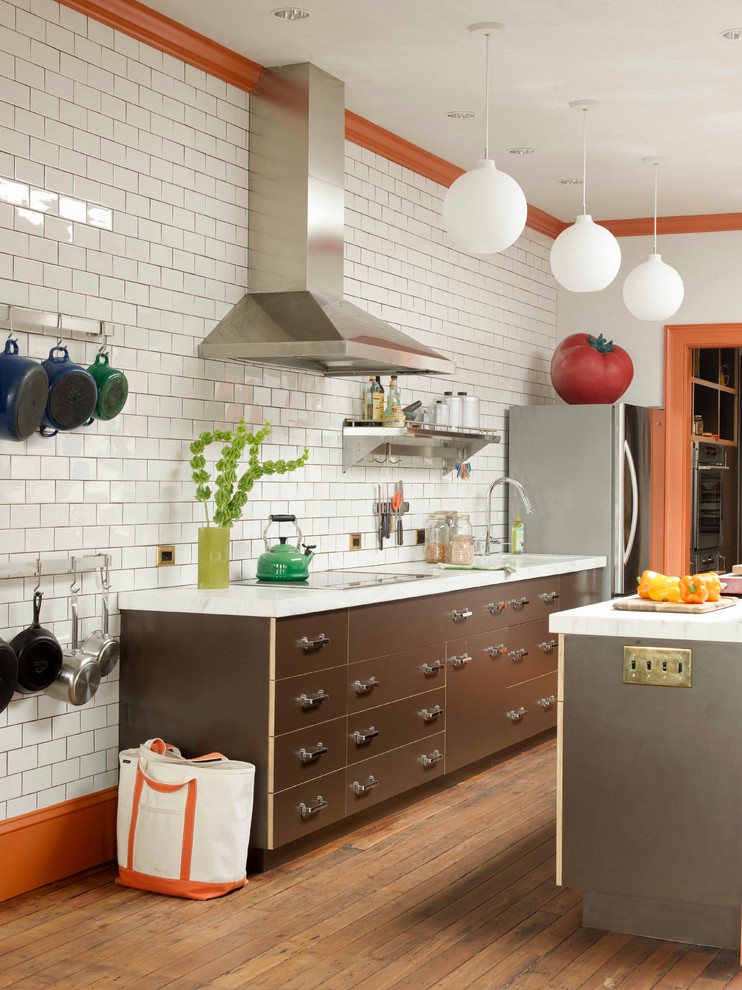 Example of a transitional galley kitchen design in New York with flat-panel cabinets, brown cabinets, marble countertops, white backsplash, subway tile backsplash and stainless steel appliances