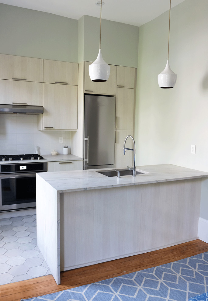 Exempel på ett mellanstort modernt kök, med en nedsänkt diskho, släta luckor, skåp i ljust trä, bänkskiva i kvartsit, vitt stänkskydd, stänkskydd i keramik, rostfria vitvaror, klinkergolv i porslin, en köksö och grått golv