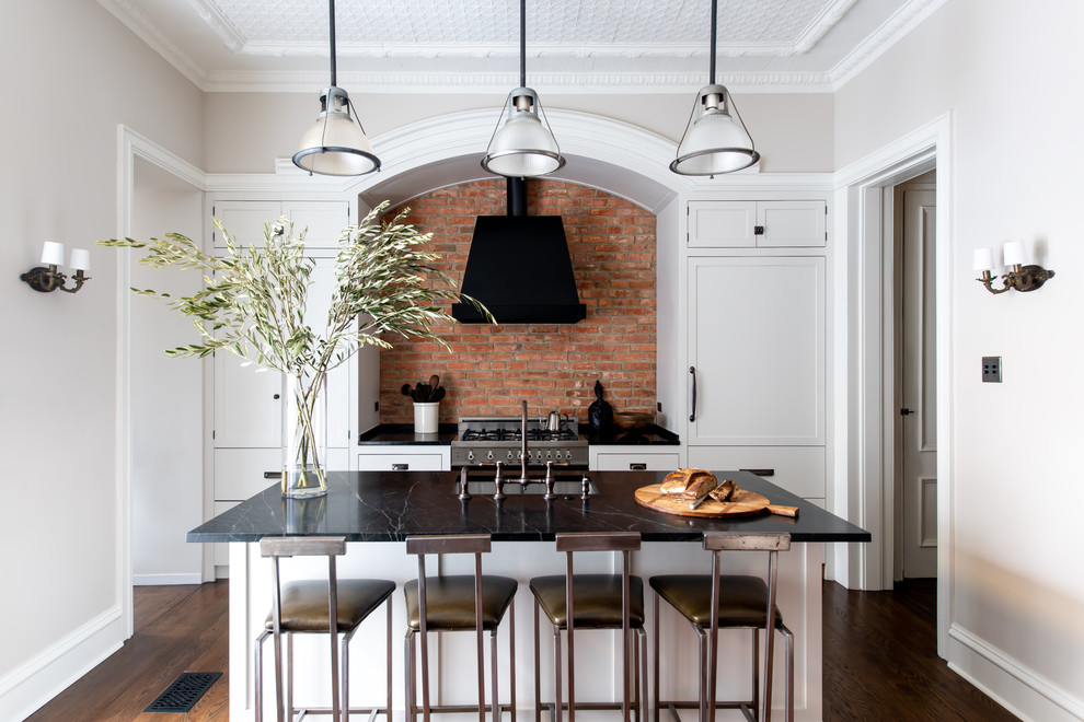 Exempel på ett mellanstort, avskilt klassiskt svart linjärt svart kök, med en undermonterad diskho, bänkskiva i täljsten, stänkskydd i tegel, en köksö, brunt golv, skåp i shakerstil, vita skåp, rött stänkskydd, integrerade vitvaror och mörkt trägolv
