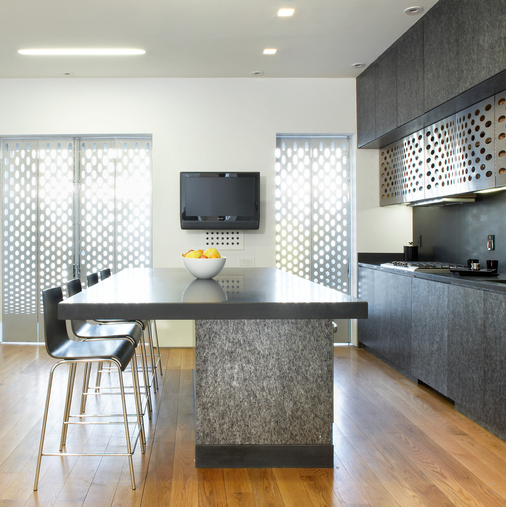 Modern inredning av ett mellanstort kök, med en undermonterad diskho, släta luckor, svarta skåp, svart stänkskydd, rostfria vitvaror, ljust trägolv, en köksö och brunt golv