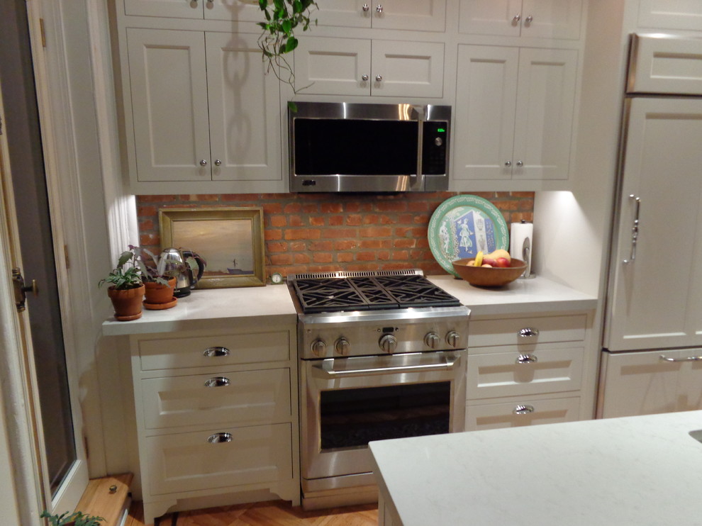 Inredning av ett klassiskt litet linjärt kök och matrum, med en enkel diskho, skåp i shakerstil, vita skåp, bänkskiva i kvarts, rostfria vitvaror, ljust trägolv och en köksö