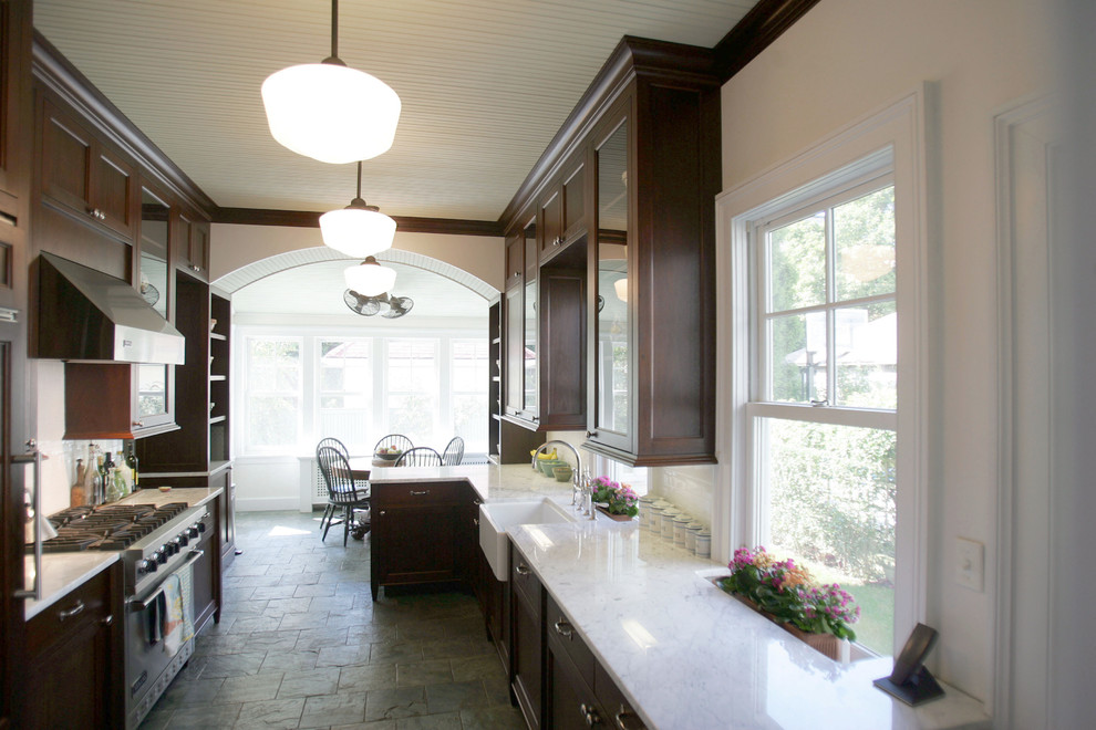 На фото: параллельная кухня среднего размера в викторианском стиле с обеденным столом, стеклянными фасадами, темными деревянными фасадами, мраморной столешницей, белым фартуком, фартуком из керамической плитки и полуостровом