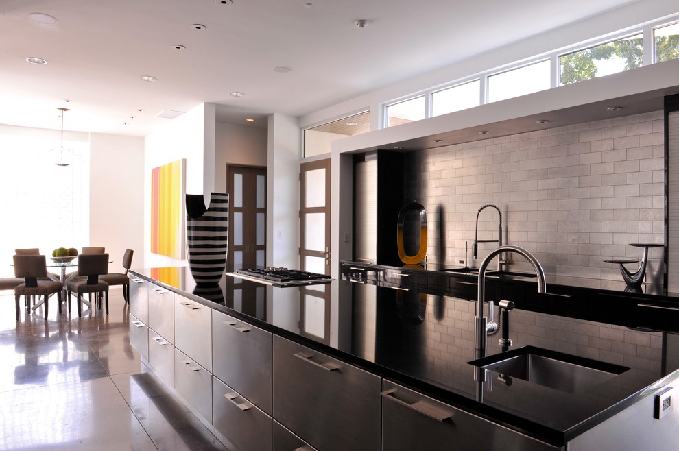 Expansive urban galley open plan kitchen in Dallas with a submerged sink, stainless steel cabinets, granite worktops, metallic splashback, metro tiled splashback, integrated appliances, flat-panel cabinets and concrete flooring.