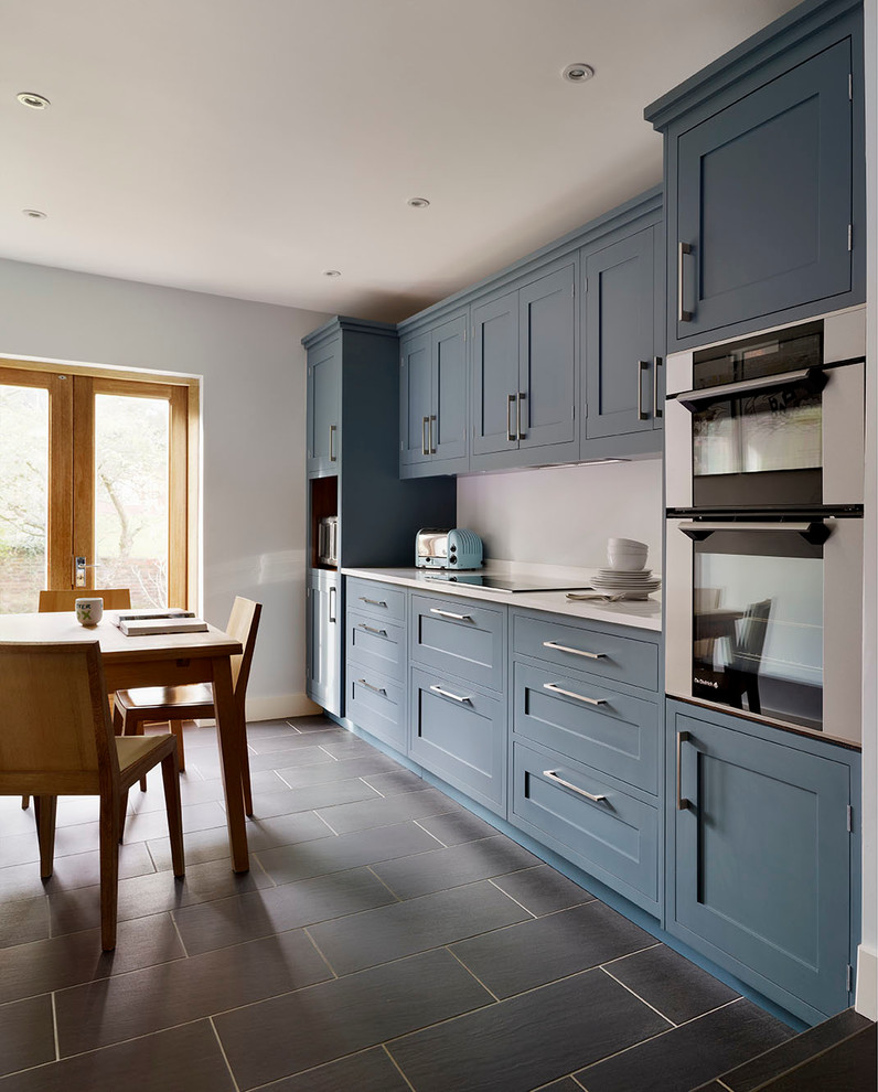 Design ideas for a large traditional single-wall kitchen/diner in London with an integrated sink, recessed-panel cabinets, blue cabinets, quartz worktops, white splashback, ceramic flooring, black floors and white worktops.