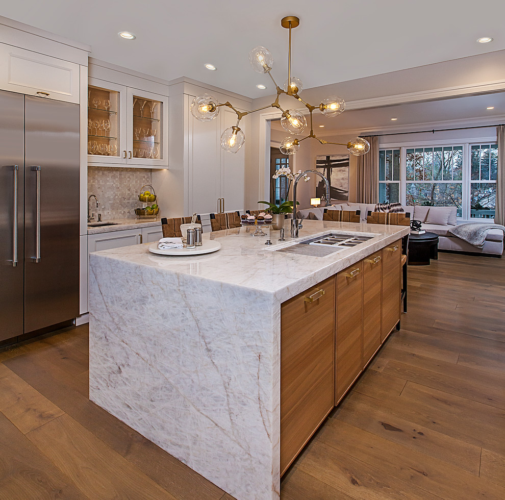 Large transitional u-shaped medium tone wood floor and brown floor enclosed kitchen photo in Detroit with an undermount sink, recessed-panel cabinets, beige cabinets, marble countertops, black backsplash, paneled appliances, an island and beige countertops