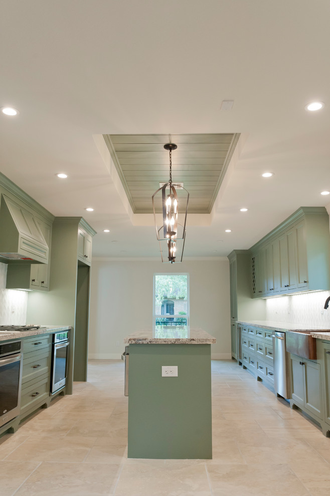 Example of a large island style galley porcelain tile kitchen design in Houston with a farmhouse sink, recessed-panel cabinets, green cabinets, granite countertops, white backsplash, glass tile backsplash, stainless steel appliances and an island