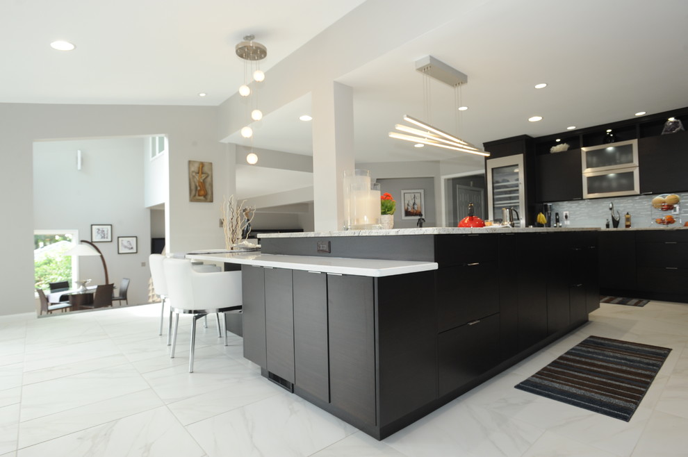 Expansive modern l-shaped kitchen/diner in Atlanta with a submerged sink, dark wood cabinets, engineered stone countertops, stainless steel appliances, porcelain flooring, an island, flat-panel cabinets, grey splashback, matchstick tiled splashback and white floors.