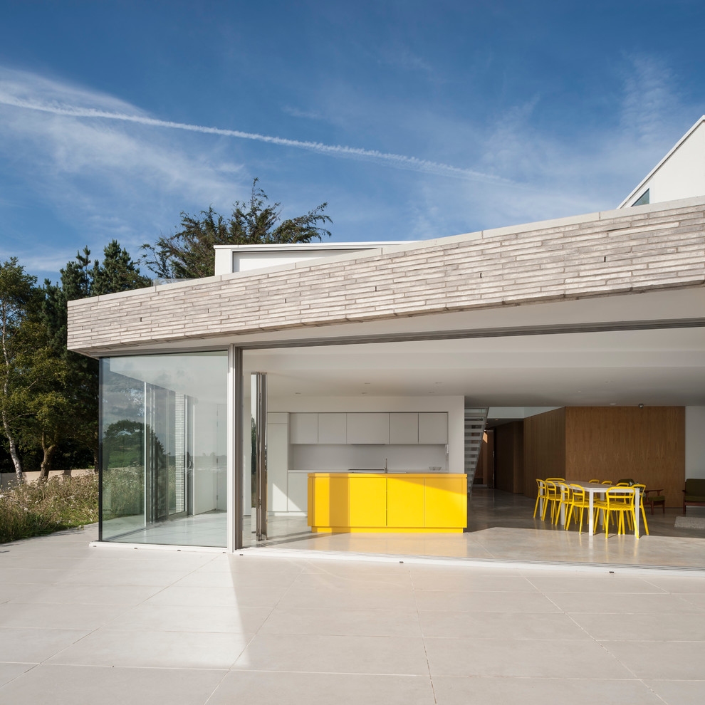 Modelo de cocina actual abierta con puertas de armario blancas, salpicadero blanco y una isla