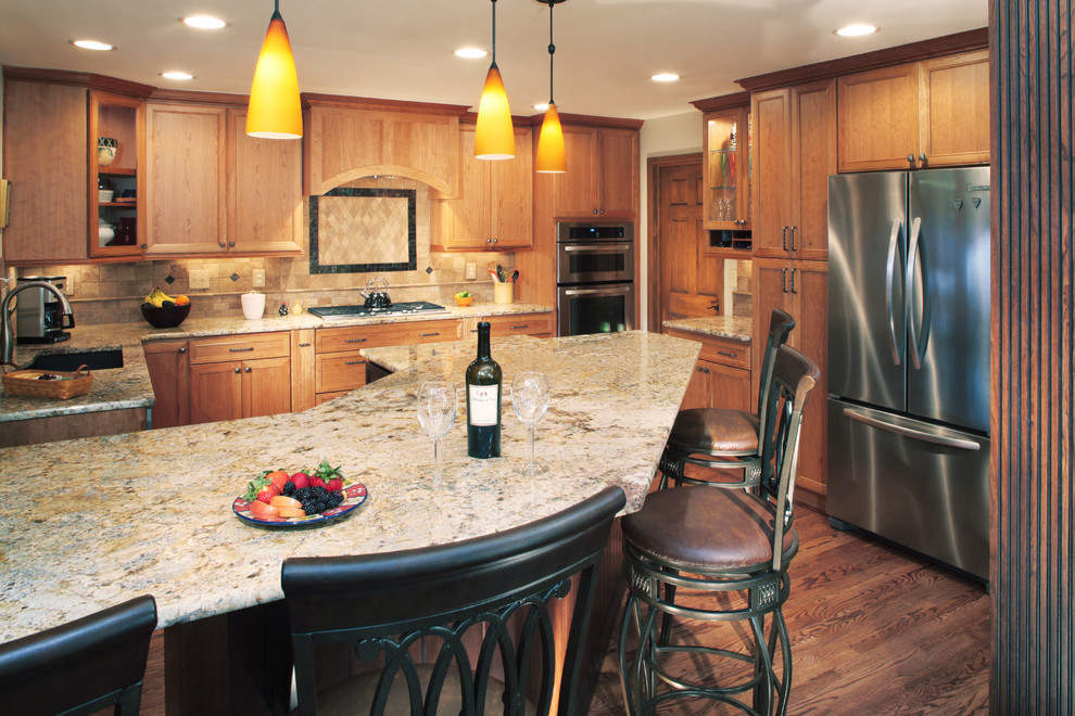 Bild på ett kök, med luckor med glaspanel, skåp i ljust trä och granitbänkskiva