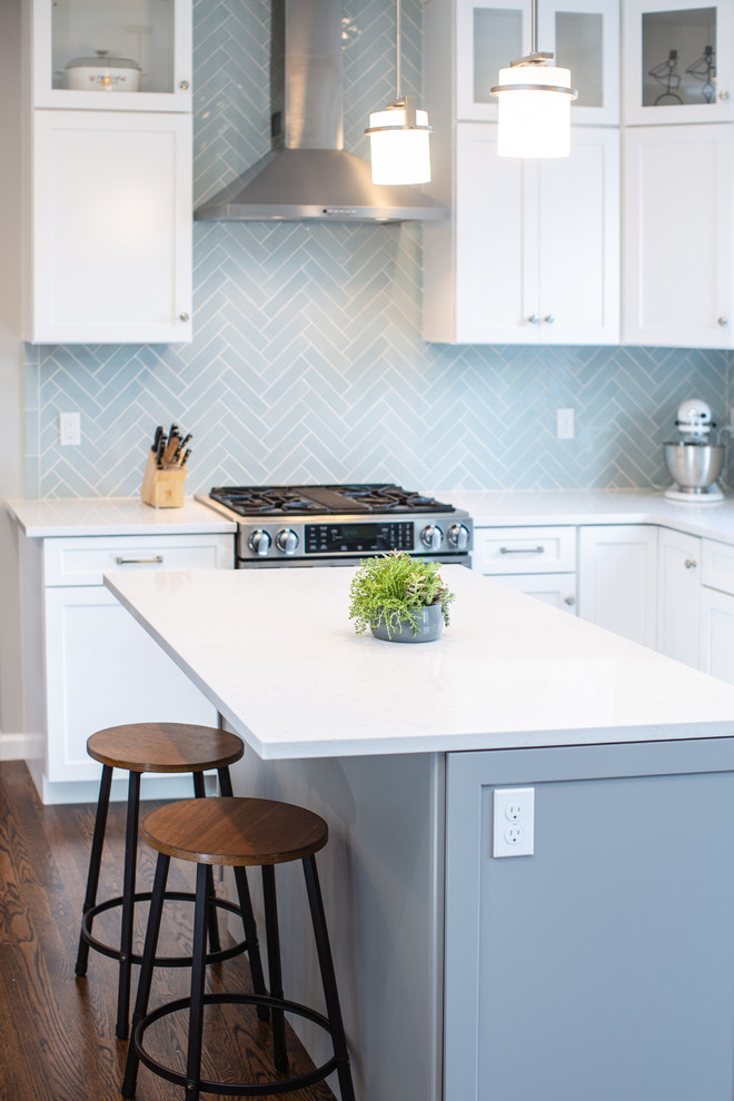 Exempel på ett avskilt, mellanstort klassiskt vit vitt u-kök, med en undermonterad diskho, skåp i shakerstil, vita skåp, bänkskiva i kvarts, blått stänkskydd, stänkskydd i keramik, rostfria vitvaror, mellanmörkt trägolv, en köksö och brunt golv