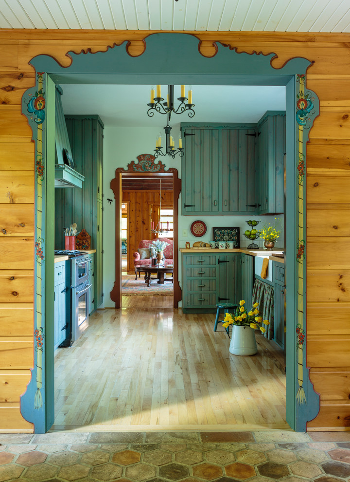 Inspiration for a mid-sized cottage galley light wood floor and brown floor kitchen remodel in Milwaukee with a farmhouse sink, flat-panel cabinets, green cabinets, wood countertops, stainless steel appliances and no island