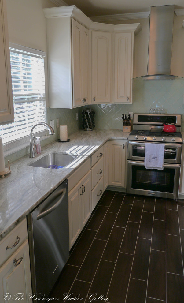 Foto på ett stort vintage kök, med en undermonterad diskho, luckor med upphöjd panel, vita skåp, marmorbänkskiva, blått stänkskydd, stänkskydd i glaskakel, rostfria vitvaror, klinkergolv i porslin och en köksö