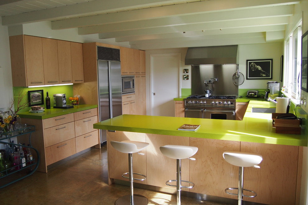 Example of a large trendy u-shaped concrete floor eat-in kitchen design in Los Angeles with an undermount sink, flat-panel cabinets, light wood cabinets, quartzite countertops, green backsplash, stone slab backsplash, stainless steel appliances and a peninsula