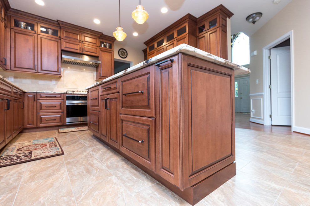 Photo of a large traditional l-shaped kitchen/diner in DC Metro with a submerged sink, raised-panel cabinets, medium wood cabinets, granite worktops, beige splashback, ceramic splashback, stainless steel appliances, ceramic flooring and an island.
