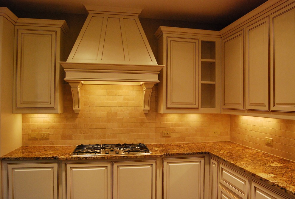 Klassisk inredning av ett kök, med skåp i rostfritt stål, granitbänkskiva, vitt stänkskydd, stänkskydd i stenkakel och rostfria vitvaror