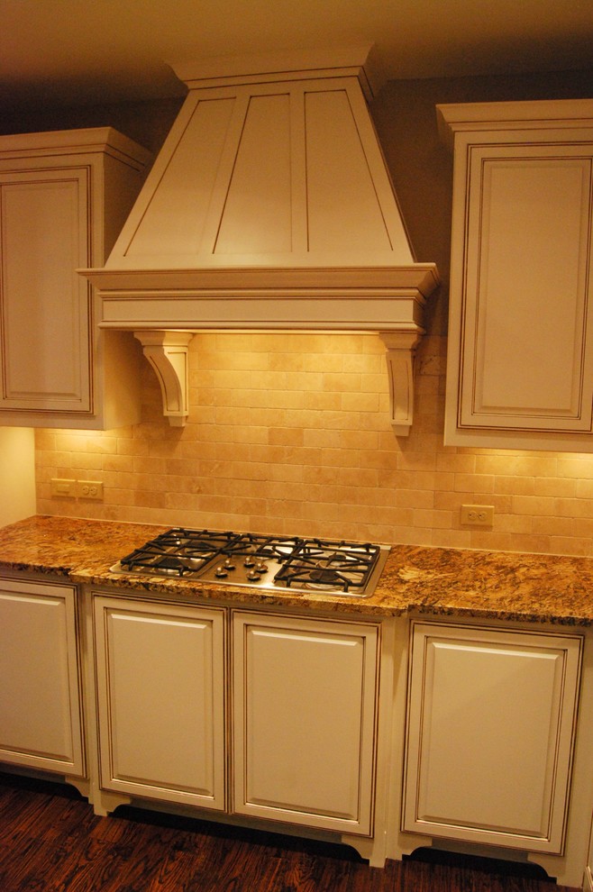 Cette photo montre une cuisine américaine chic en U et inox avec un plan de travail en granite, une crédence blanche, une crédence en carrelage de pierre et un électroménager en acier inoxydable.