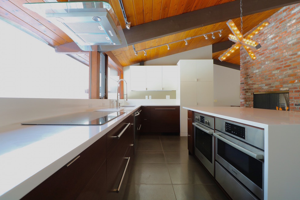 Foto på ett avskilt, stort funkis l-kök, med en undermonterad diskho, släta luckor, vita skåp, bänkskiva i kvarts, vitt stänkskydd, rostfria vitvaror, betonggolv och en köksö