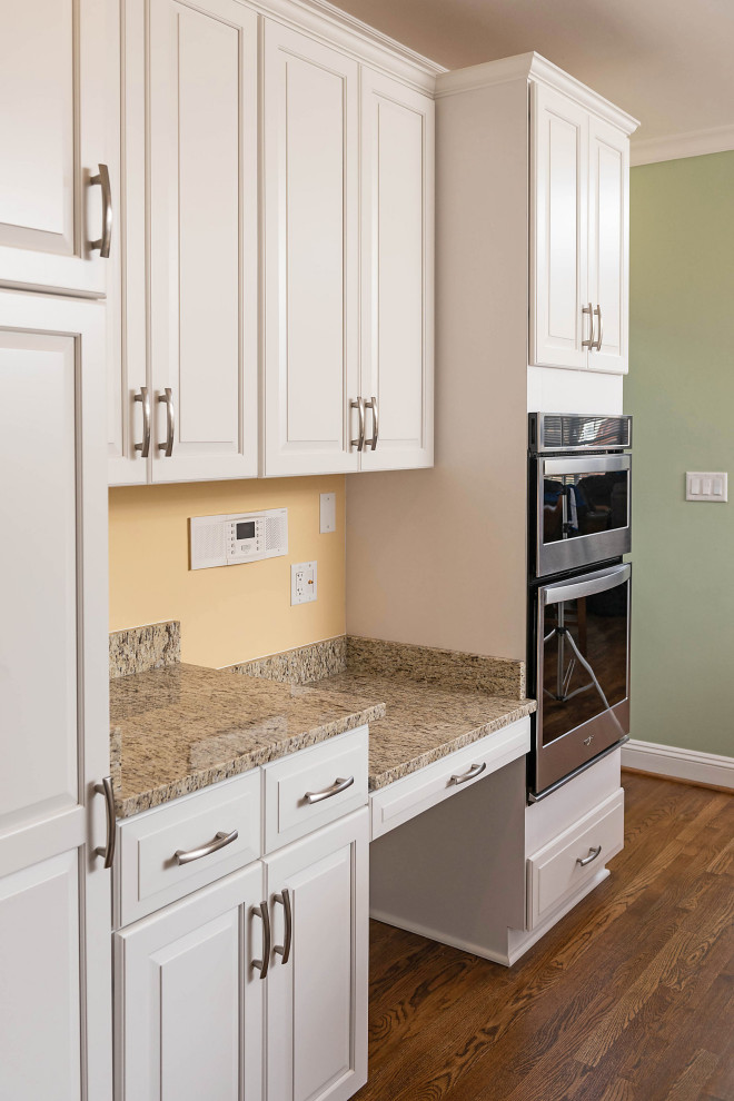 Exempel på ett avskilt, mellanstort klassiskt beige beige l-kök, med en undermonterad diskho, luckor med upphöjd panel, vita skåp, granitbänkskiva, rostfria vitvaror, mellanmörkt trägolv, en köksö och brunt golv