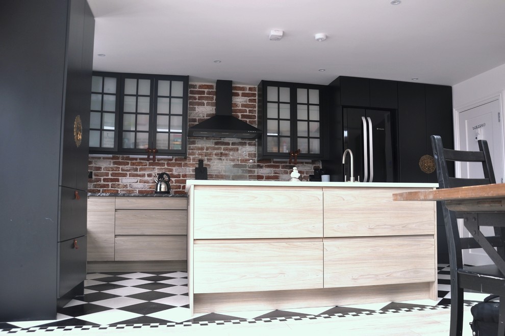 Foto di una cucina industriale di medie dimensioni con lavello integrato, ante lisce, ante nere, top in superficie solida, paraspruzzi in mattoni, elettrodomestici neri e pavimento con piastrelle in ceramica