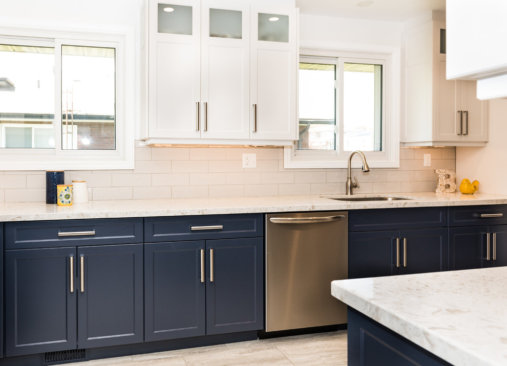 Exemple d'une cuisine moderne avec un évier encastré, un placard à porte shaker, des portes de placard bleues, un plan de travail en surface solide, une crédence blanche, un électroménager en acier inoxydable, un sol en vinyl, un sol multicolore et un plan de travail blanc.