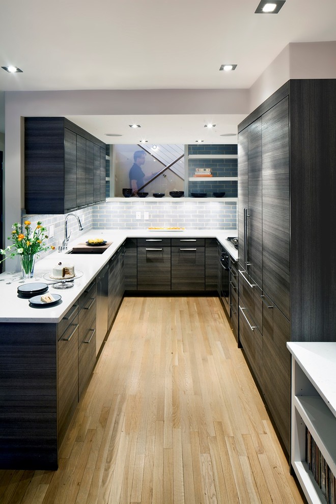 Enclosed kitchen - mid-sized modern u-shaped light wood floor enclosed kitchen idea in New York with an undermount sink, flat-panel cabinets, gray backsplash, ceramic backsplash, no island, solid surface countertops, paneled appliances and black cabinets