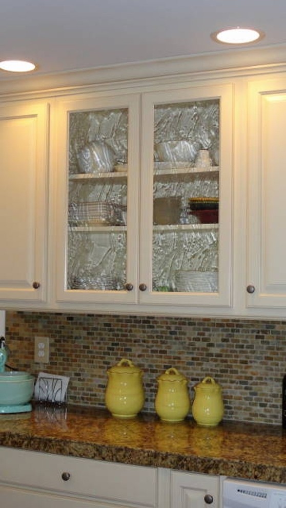 Klassisk inredning av ett mellanstort kök, med en undermonterad diskho, luckor med upphöjd panel, vita skåp, granitbänkskiva, flerfärgad stänkskydd, stänkskydd i mosaik, rostfria vitvaror, mörkt trägolv och en köksö