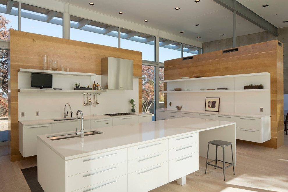Photo of a large contemporary u-shaped kitchen/diner in Austin with a submerged sink, open cabinets, white cabinets, engineered stone countertops, white splashback, stainless steel appliances, light hardwood flooring and an island.