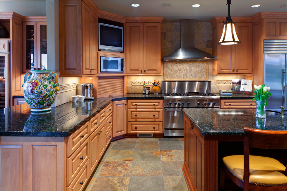 Example of a large classic l-shaped slate floor and multicolored floor kitchen design in Portland with an undermount sink, raised-panel cabinets, medium tone wood cabinets, granite countertops, brown backsplash, ceramic backsplash, stainless steel appliances and an island