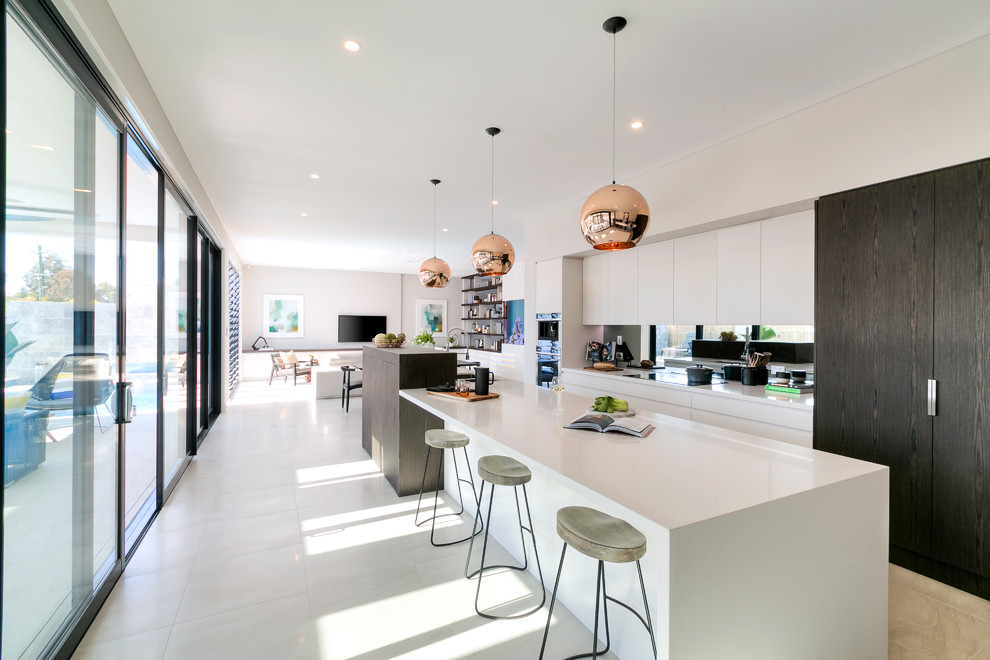 Cette photo montre une cuisine ouverte parallèle tendance avec un placard à porte plane, des portes de placard blanches, un électroménager en acier inoxydable et îlot.