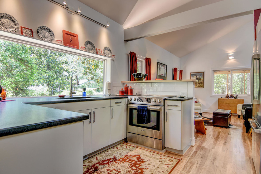 Photo of a medium sized classic u-shaped kitchen/diner in Other with a submerged sink, white cabinets, white splashback, stainless steel appliances, light hardwood flooring and no island.