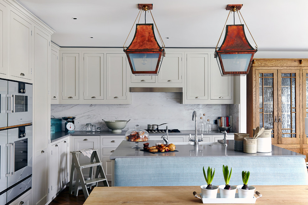 Inspiration for a transitional u-shaped kitchen remodel in London with a double-bowl sink, shaker cabinets and stone slab backsplash