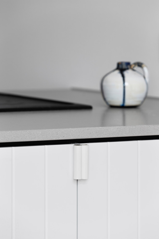 Foto på ett funkis kök, med en integrerad diskho, släta luckor, svarta skåp, bänkskiva i betong, vitt stänkskydd, stänkskydd i marmor, rostfria vitvaror, mellanmörkt trägolv, en halv köksö och brunt golv