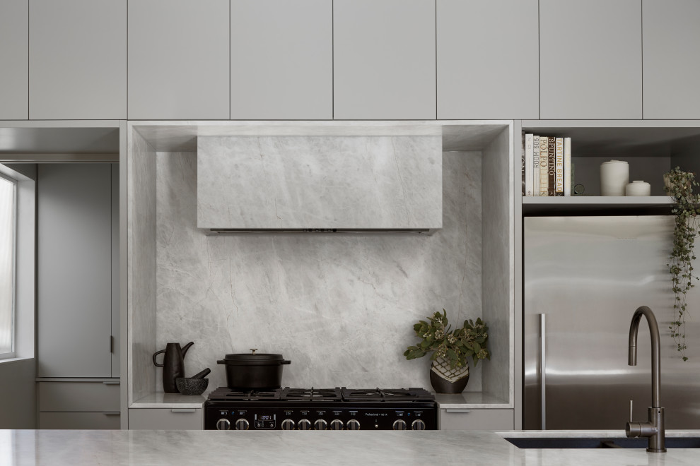 Modern inredning av ett litet vit vitt l-kök, med en nedsänkt diskho, grå skåp, marmorbänkskiva, grått stänkskydd, stänkskydd i marmor, rostfria vitvaror och ljust trägolv
