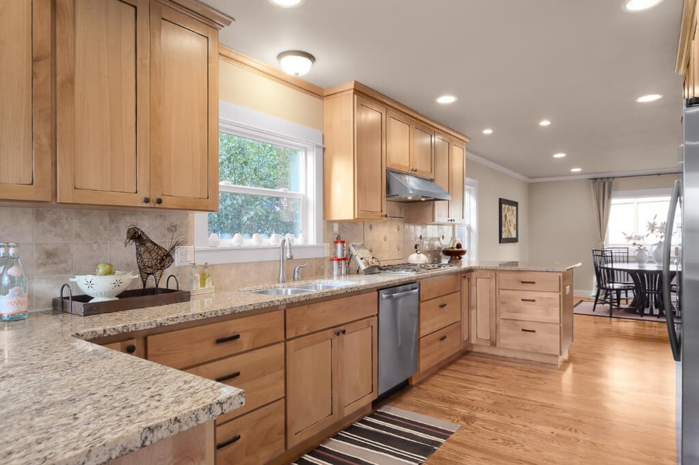 Example of a mid-sized classic galley light wood floor and beige floor enclosed kitchen design in Seattle with an undermount sink, shaker cabinets, light wood cabinets, granite countertops, beige backsplash, ceramic backsplash, stainless steel appliances, no island and beige countertops