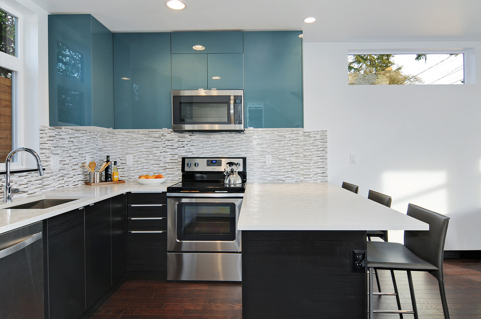 Inspiration for a small modern u-shaped dark wood floor and brown floor open concept kitchen remodel in Seattle with an undermount sink, flat-panel cabinets, blue cabinets, quartz countertops, beige backsplash, ceramic backsplash, stainless steel appliances and white countertops