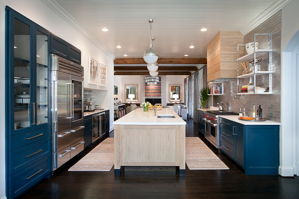 Exempel på ett stort klassiskt kök, med luckor med infälld panel, blå skåp, rostfria vitvaror, mörkt trägolv, en köksö, en undermonterad diskho, bänkskiva i kvarts, stänkskydd med metallisk yta och stänkskydd i tunnelbanekakel