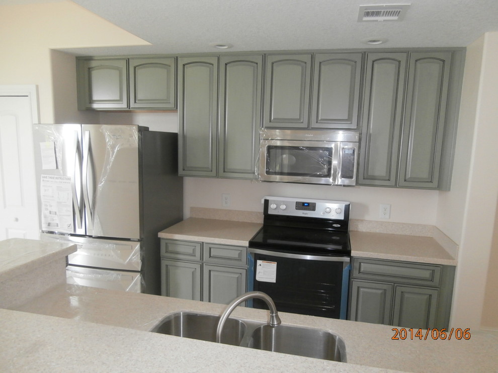 Medium sized traditional galley kitchen/diner in Orlando with a submerged sink, recessed-panel cabinets, green cabinets, composite countertops, beige splashback, stone slab splashback, stainless steel appliances, porcelain flooring and an island.